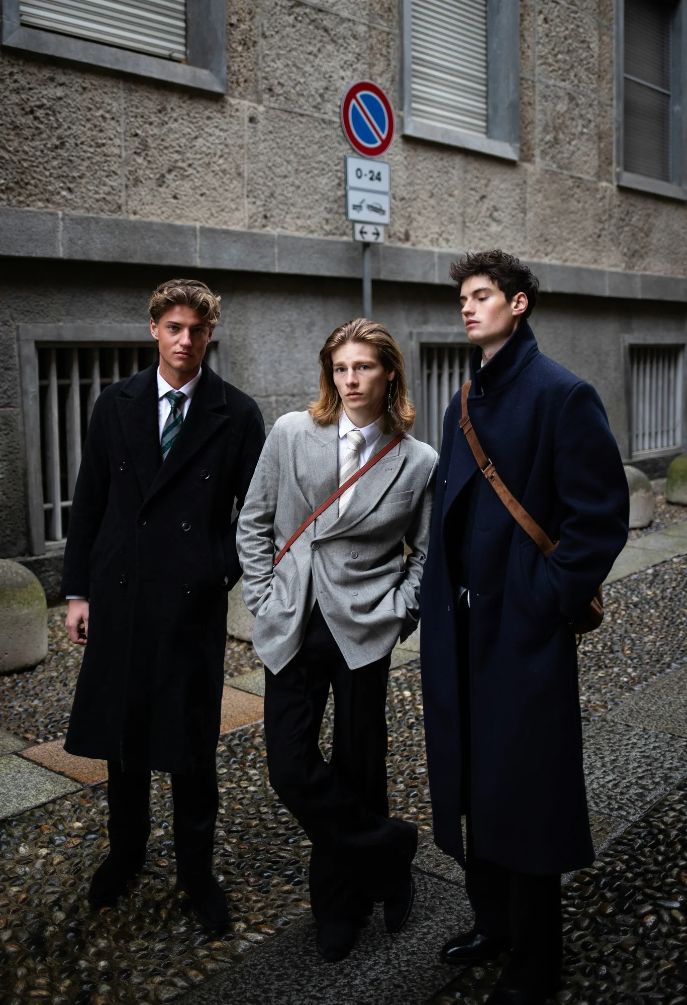 Three fashion attendees in tailored coats on a Milan street